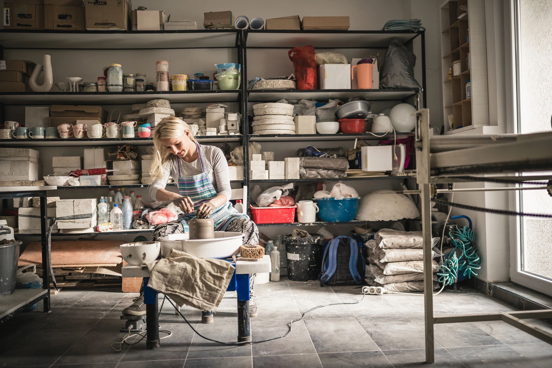 Artist shaping clay on a pottery wheel in a studio